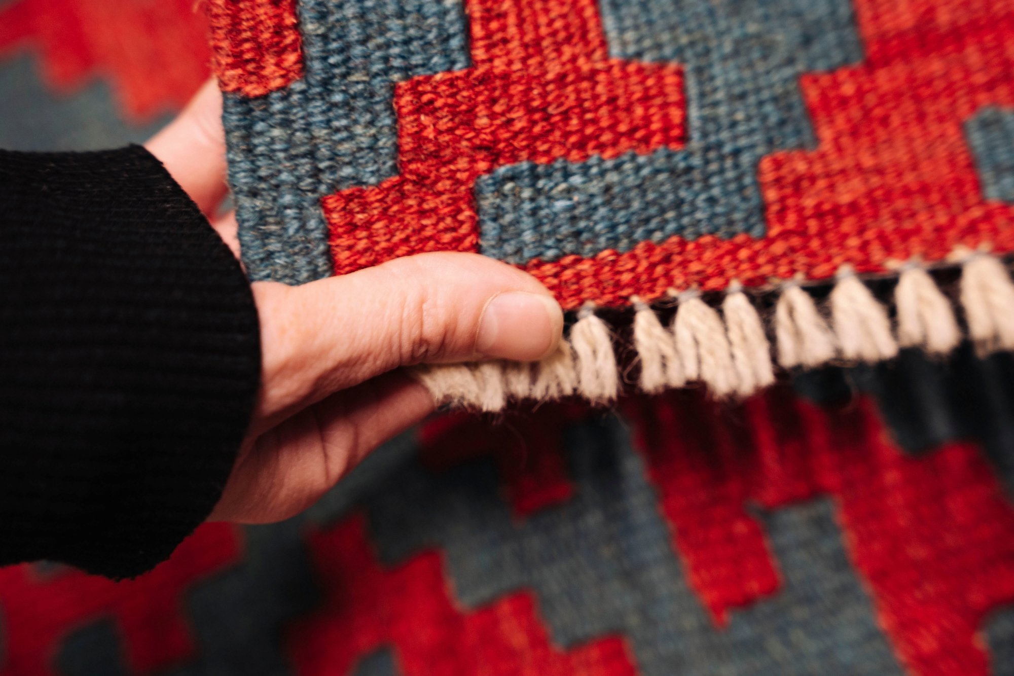 A technician inspecting the fringe and pile of an Oriental rug before washing