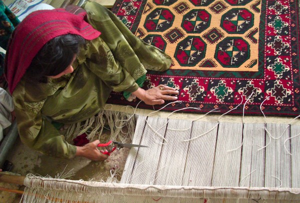 A weaver cutting a finished Oriental rug from the loom