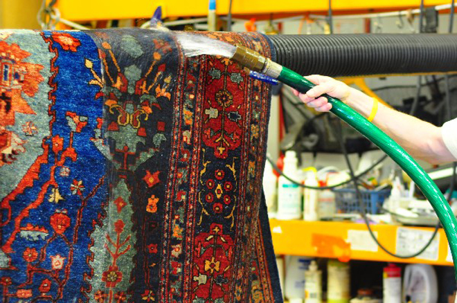 A rug being rinsed with clean water in the wash plant
