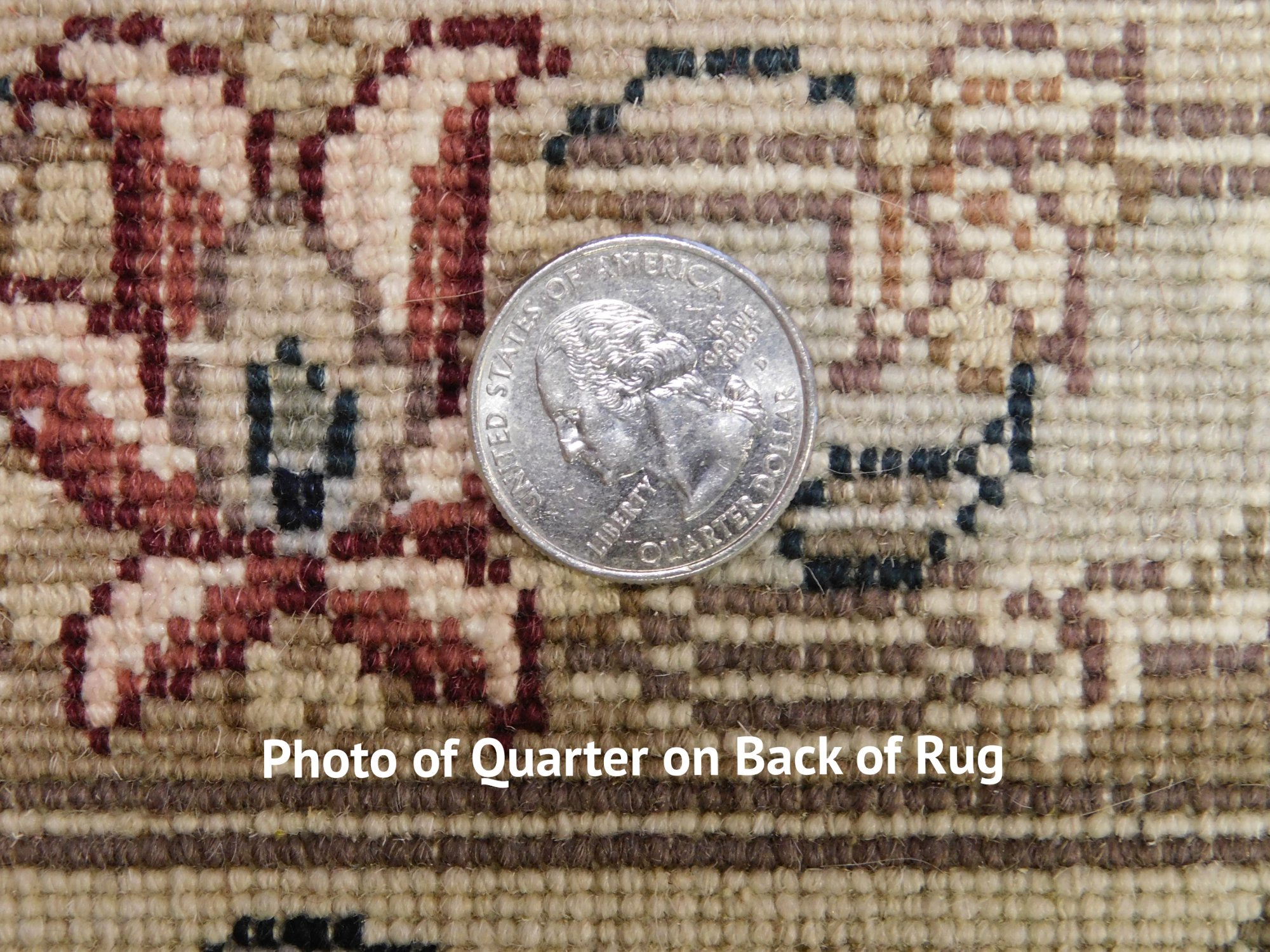 The back of a rug with a quarter placed on the knots for scale