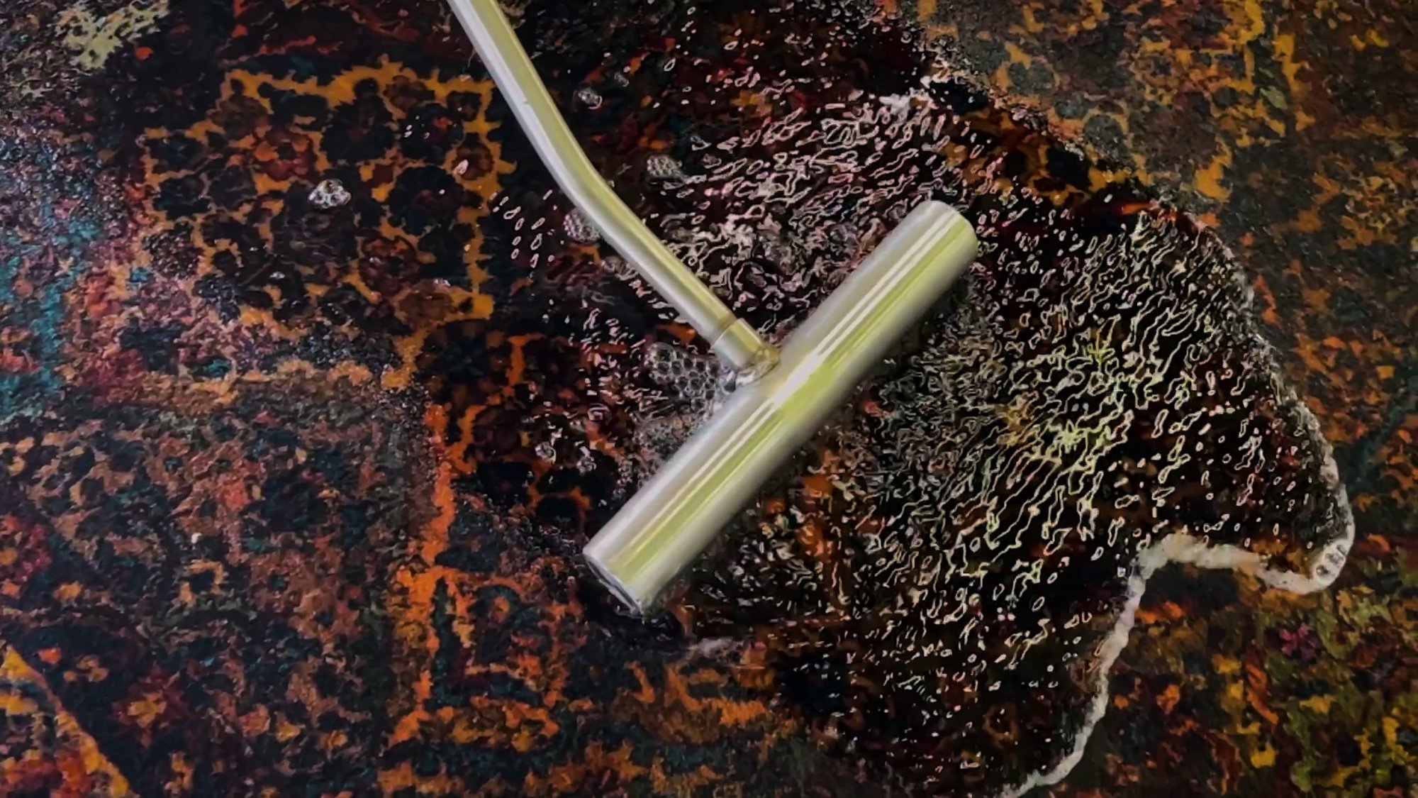 A wash wand drawing soapy water from a hand-washed Oriental rug at Oriental Rug Salon